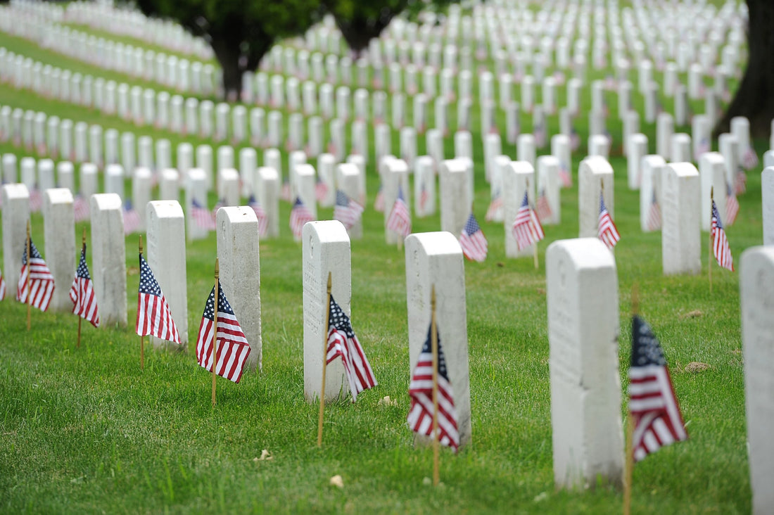 Rows of white gravestones adorned with small American flags, symbolizing Memorial Day remembrance and honor.