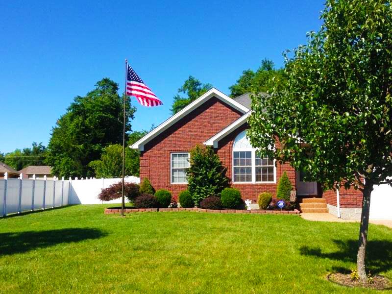A dark bronze colored flagpole in front of a red brick home