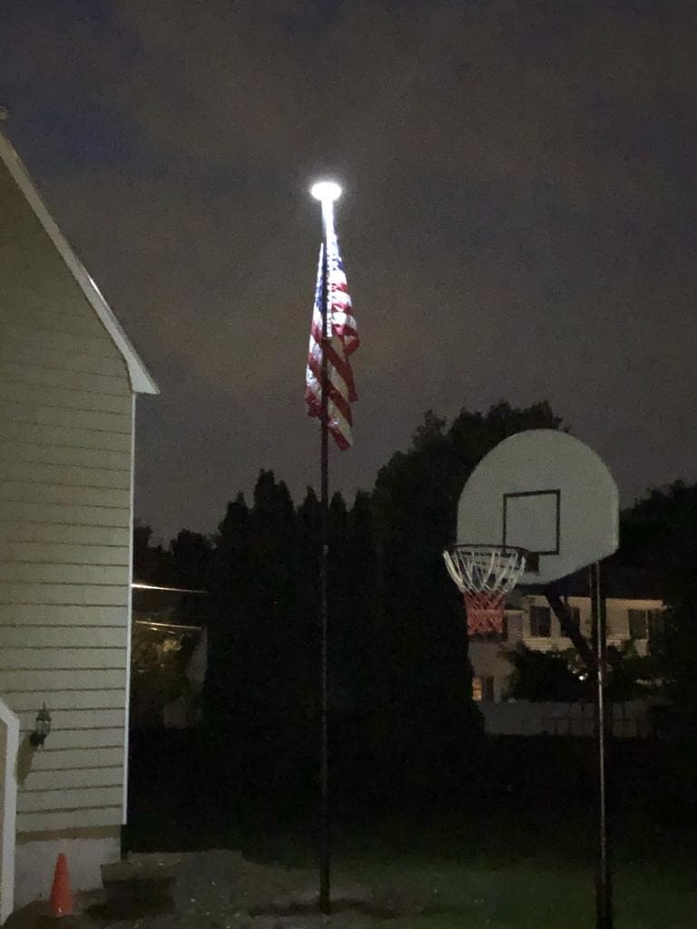 White solar flagpole lighting system by Atlantic Flagpole for bright illumination of flags