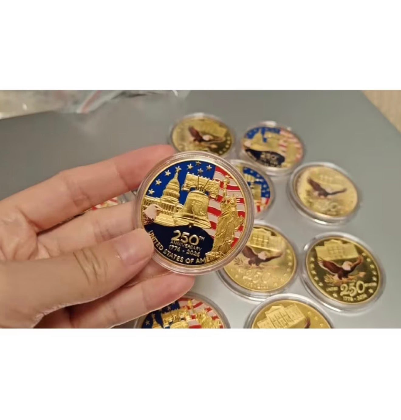 America 250 Challenge Coin held in hand alongside a collection of coins in capsules