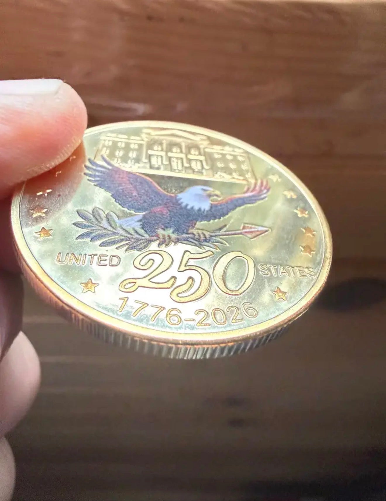 America 250 Challenge Coin reverse eagle design shown at an angle on a wood tabletop