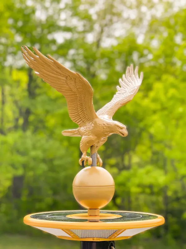 A gold eagle flagpole topper above a solar light
