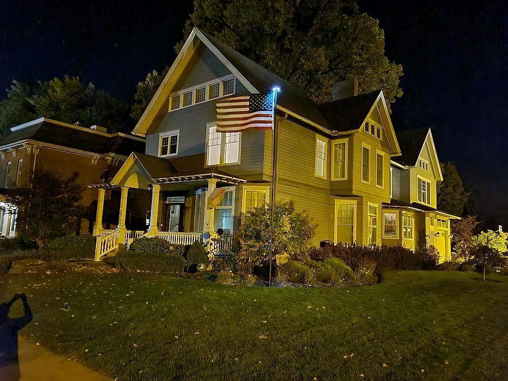 A Phoenix flagpole with a solar light keeping the American flag lit at night in front of a house