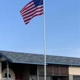 A tall flagpole flying the American flag in front of a business